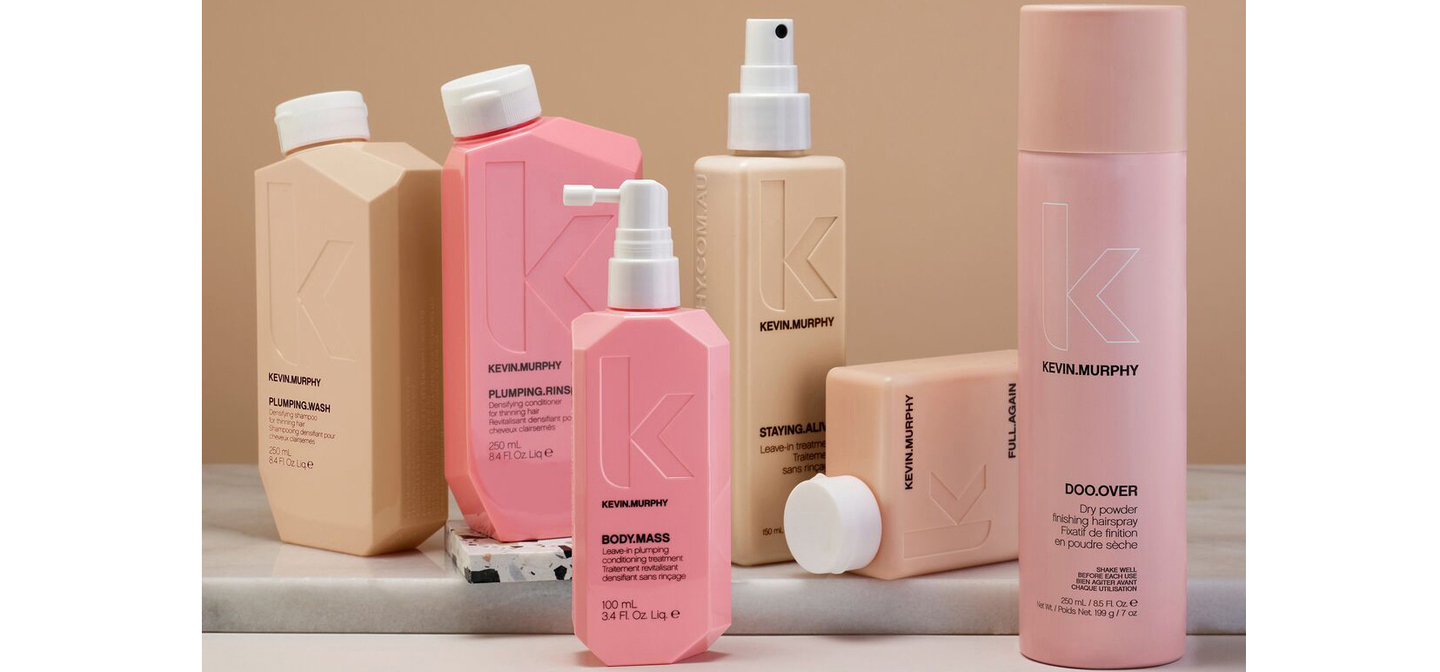 A range of Kevin Murphy hair care products in soft pink and beige packaging against a peach background